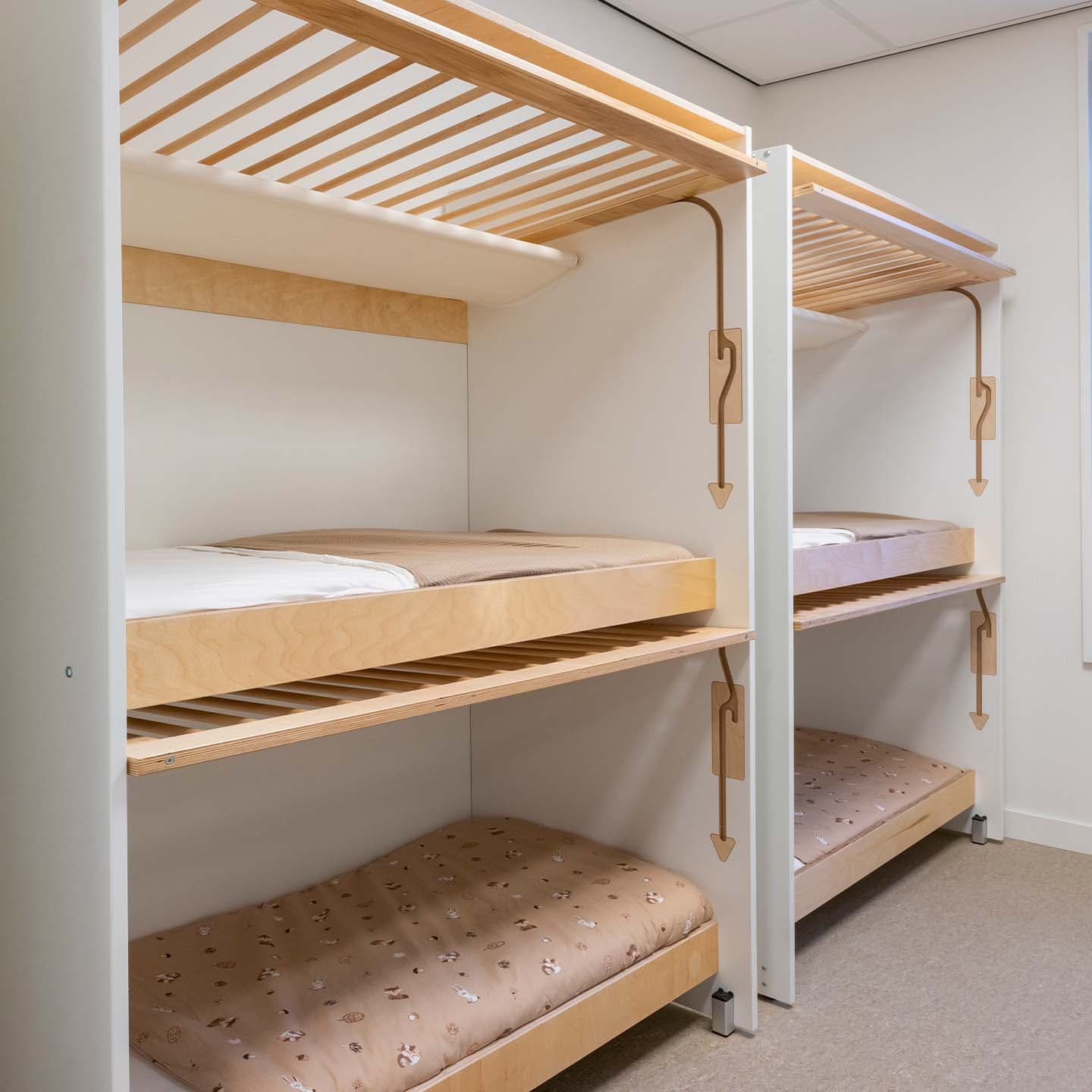 Slaapruimte in de kinderopvang met twee houten opgemaakte stapelbedden waar nog hekwerken voor kunnen geschoven worden.