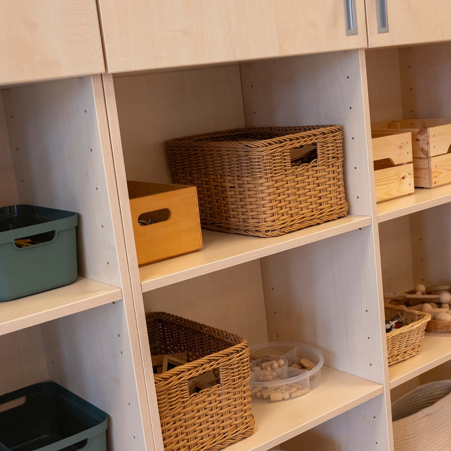 Houten opbergkasten met verschillende opbergmanden en opbergbakken, netjes opgesteld in een lichte ruimte.