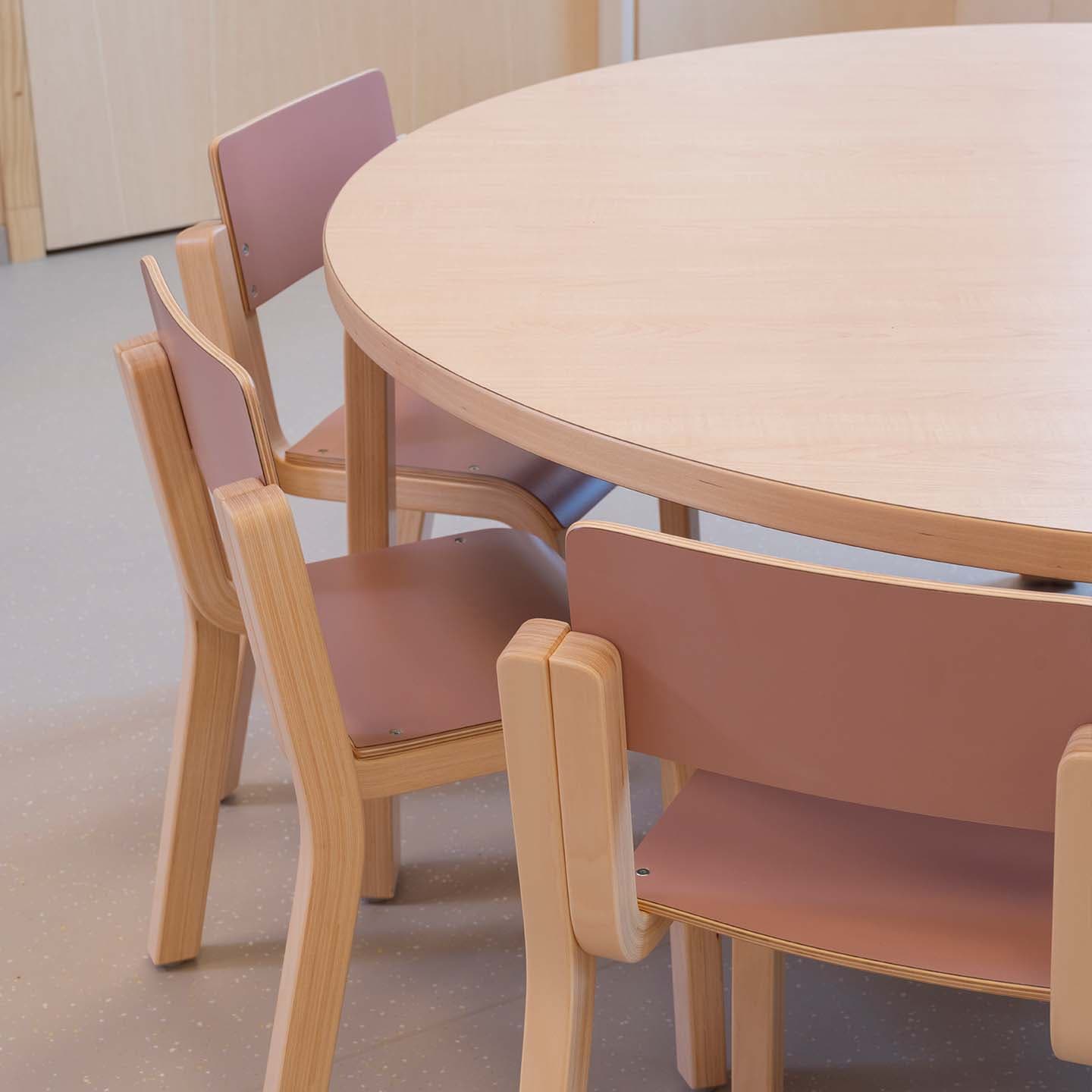 Ronde houten kindertafel met drie bijpassende kinderstoelen, allemaal uitgevoerd met zachte, afgeronde vormen.