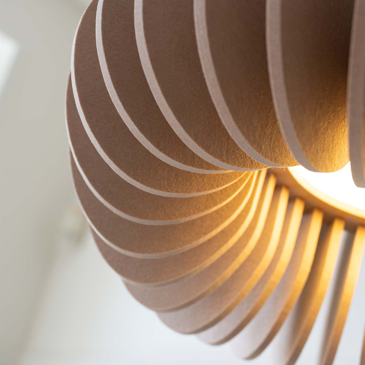 Close-up van een moderne hanglamp met een spiraalvormig houten ontwerp dat een warme gloed verspreidt.